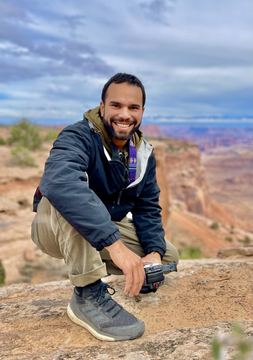 Rivera, Enrique_Photo1 Photo of Enrique Rivera crouching on a landscape on a sunny day
